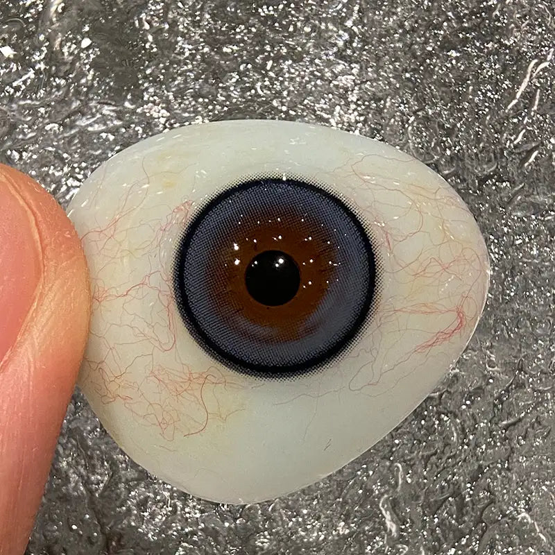 Observing the sheer blue and fine black limbal ring on a fingertip to show the premium colored contacts quality.