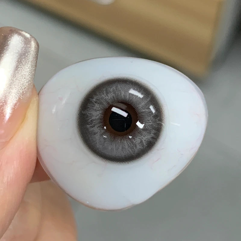 Real-life view of the soft, icy-grey tint on fingertip, showing the authentic quality of this chic lens collection.