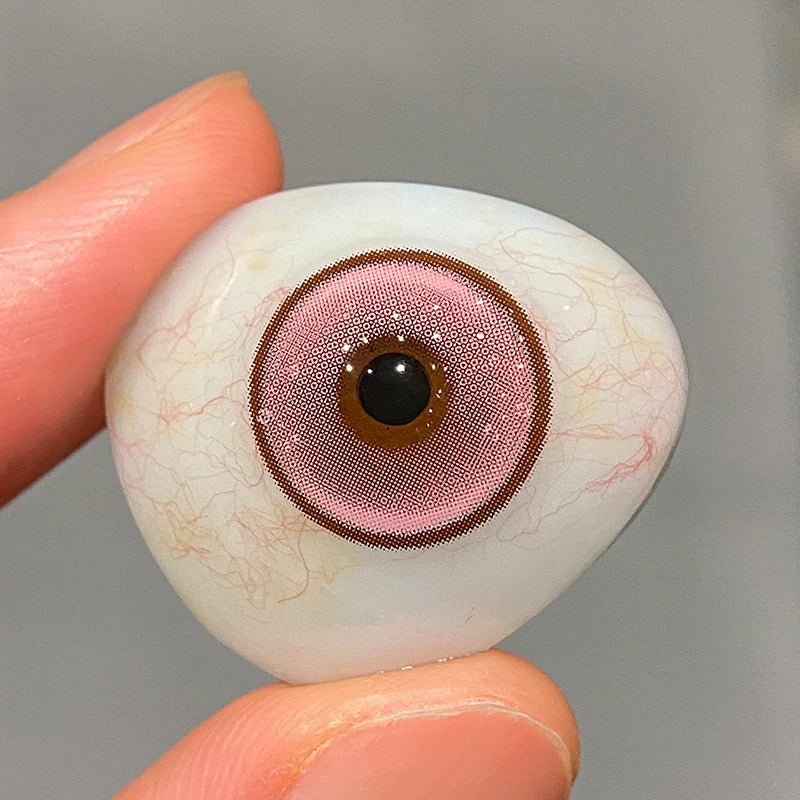 Inspecting the intense pink tint on a fingertip to show the superior pigment of these lenses.