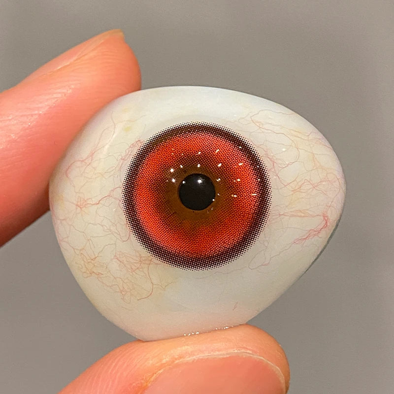 Observing the red and black pigment on a fingertip to show the premium quality of these colored contacts.