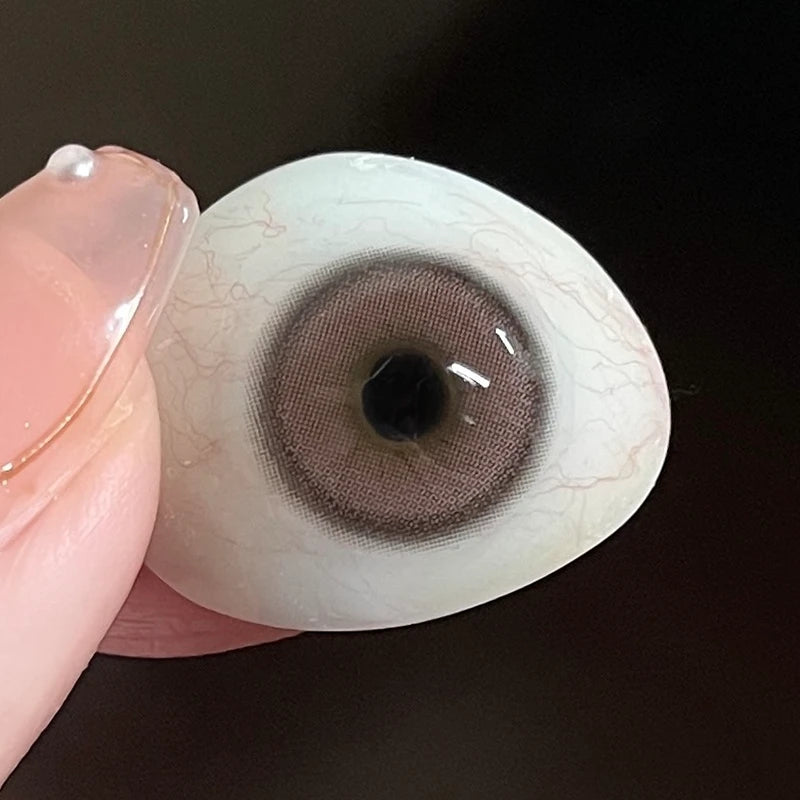 Showcasing the authentic, matte-pink pigment on a fingertip to confirm the premium lens texture.