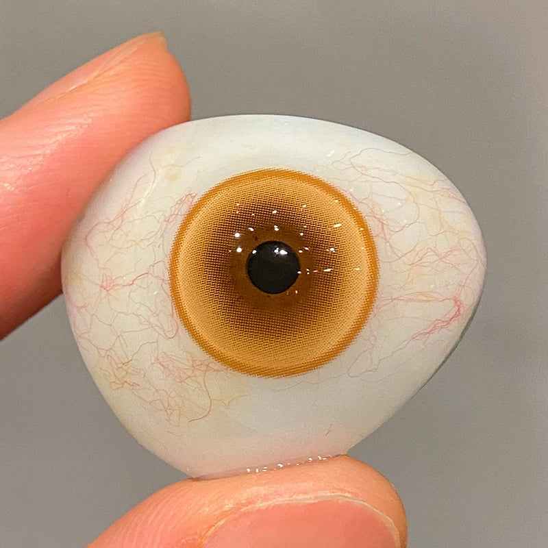 Checking the bright, honey-gold tint on a fingertip to show the premium craftsmanship of these colored contacts.