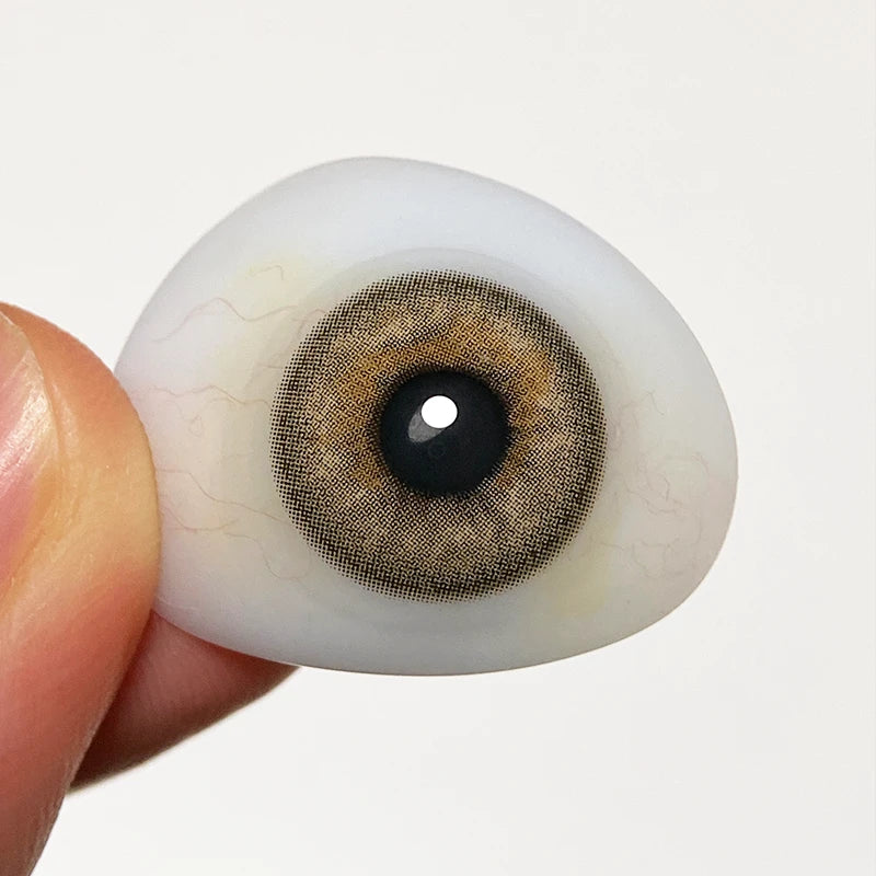 Inspecting the intense, cool-brown shade on a fingertip to confirm the premium quality of these lenses.