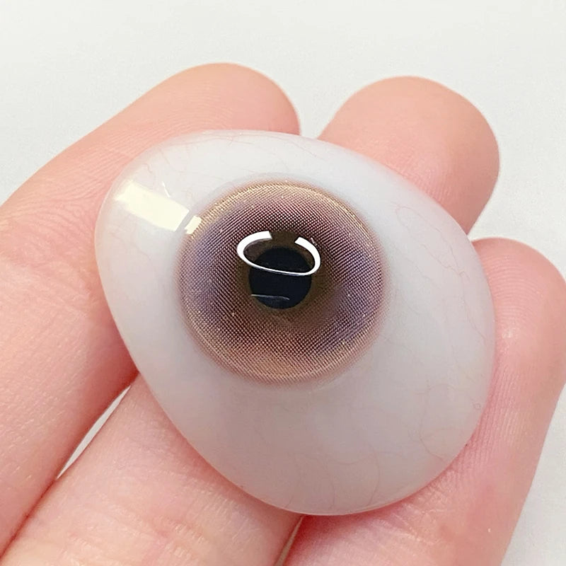 Inspecting the sheer pink pigment on a fingertip to confirm the premium craftsmanship of these colored contacts.